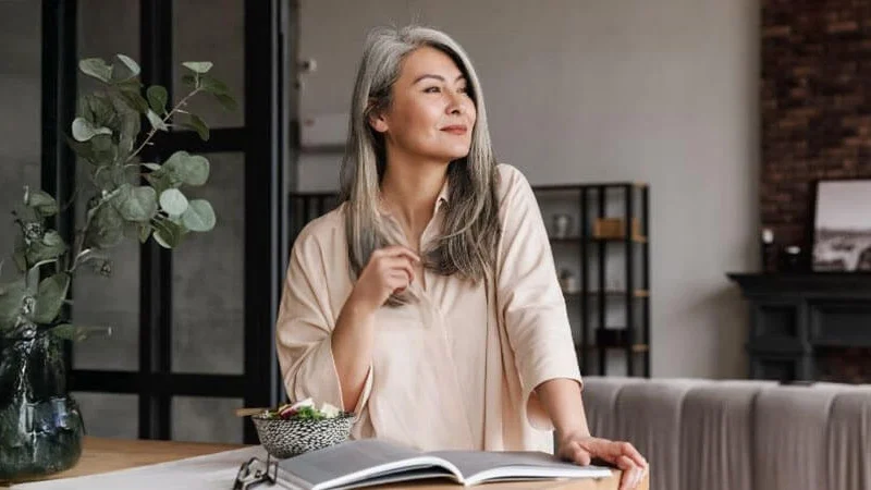 Woman standing in a modern living room, looking out the window, representing probate exemptions. Learn more in our complete guide. Contact Kid Breukelen Realty Group for guidance.