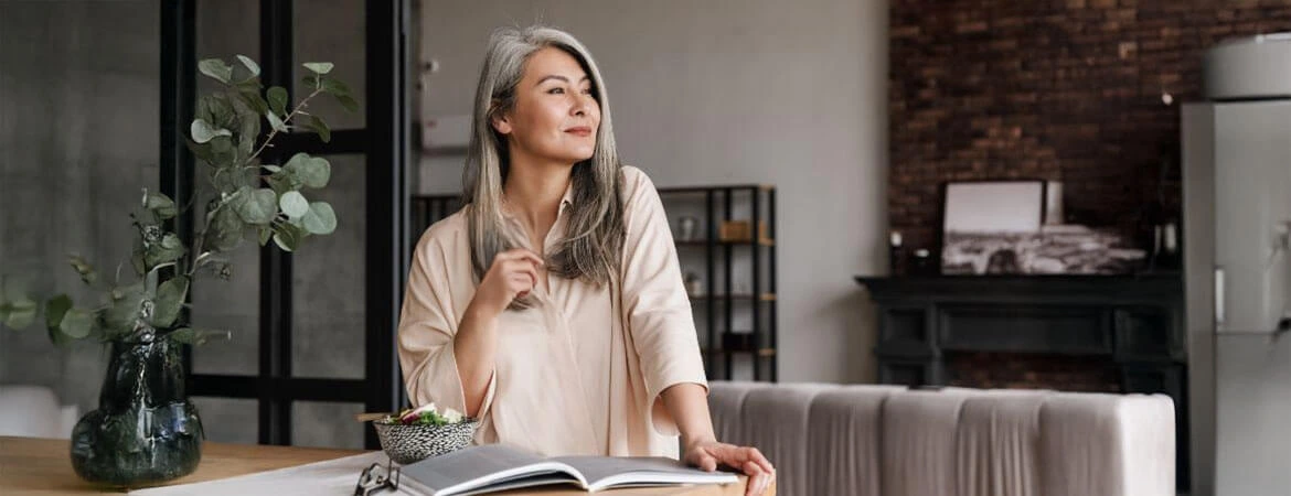A woman standing in a modern living room, gazing out the window, reflecting on probate exemptions. Discover more in our complete guide on probate exemptions. Reach out to Kid Breukelen Realty Group for expert assistance.