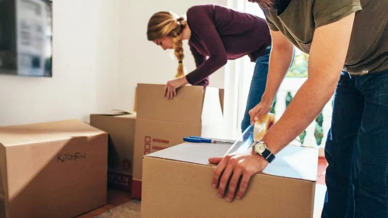 Couple packing boxes, symbolizing the careful organization of probate estate belongings after death. Contact Kid Breukelen Realty Group for professional assistance.